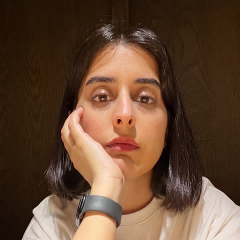 Zahra, resting her cheek on her hand, looking at the camera